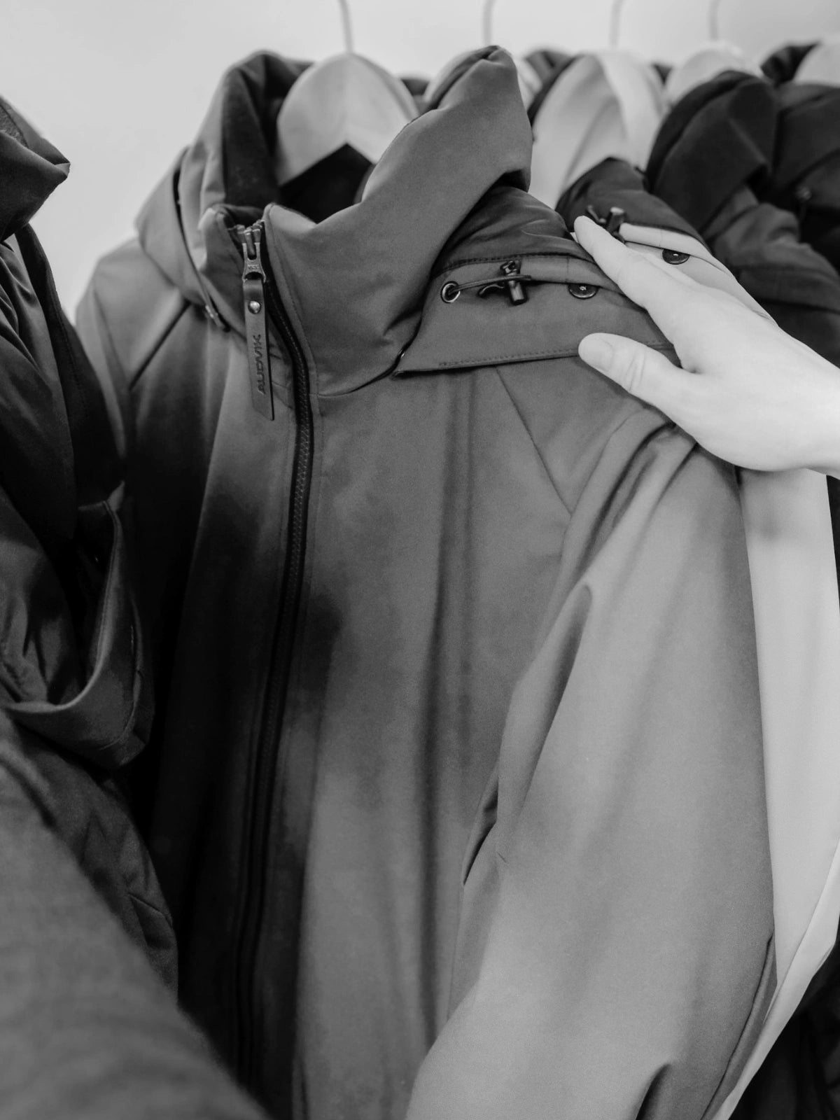 Photo en noir et blanc d'une main touchant un manteau audvik.