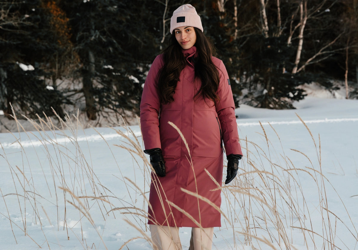 Femme dans un paysage hivernal portant le manteau d'hiver long Paris en couleur rose boréale.