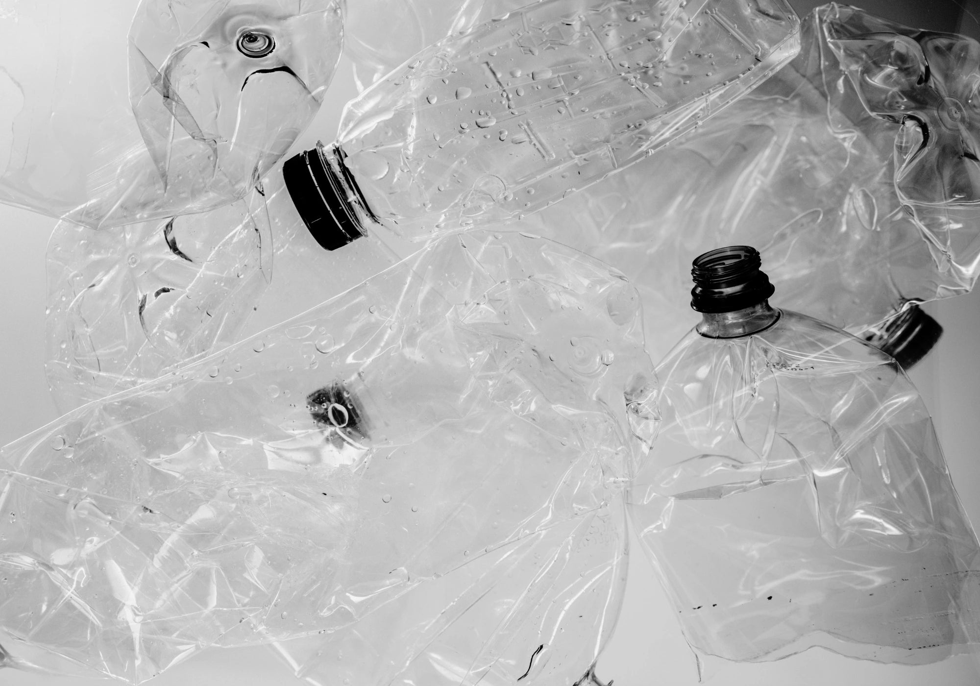photo en noir et blanc de bouteilles en plastique écrasées utilisées pour créer les tissus écoresponsables Audvik. 