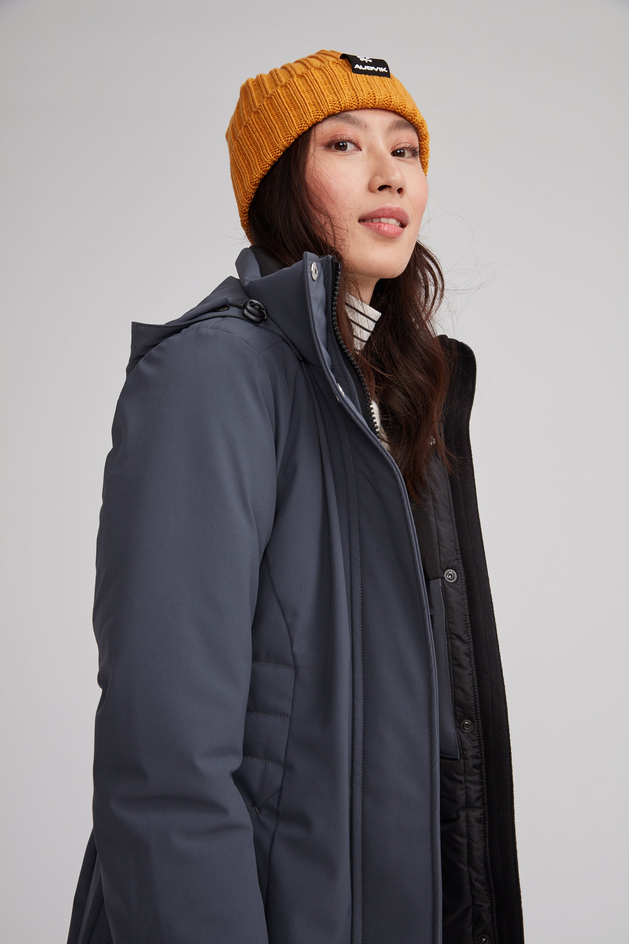 Manteau d'hiver mi-long pour femme. Manteau d'hiver fait au Québec, fait à partir de tissu performant. Manteau Imperméable, manteau coupe-vent et manteau respirant. Isolant synthétique et vegan. Manteau chaud gris.